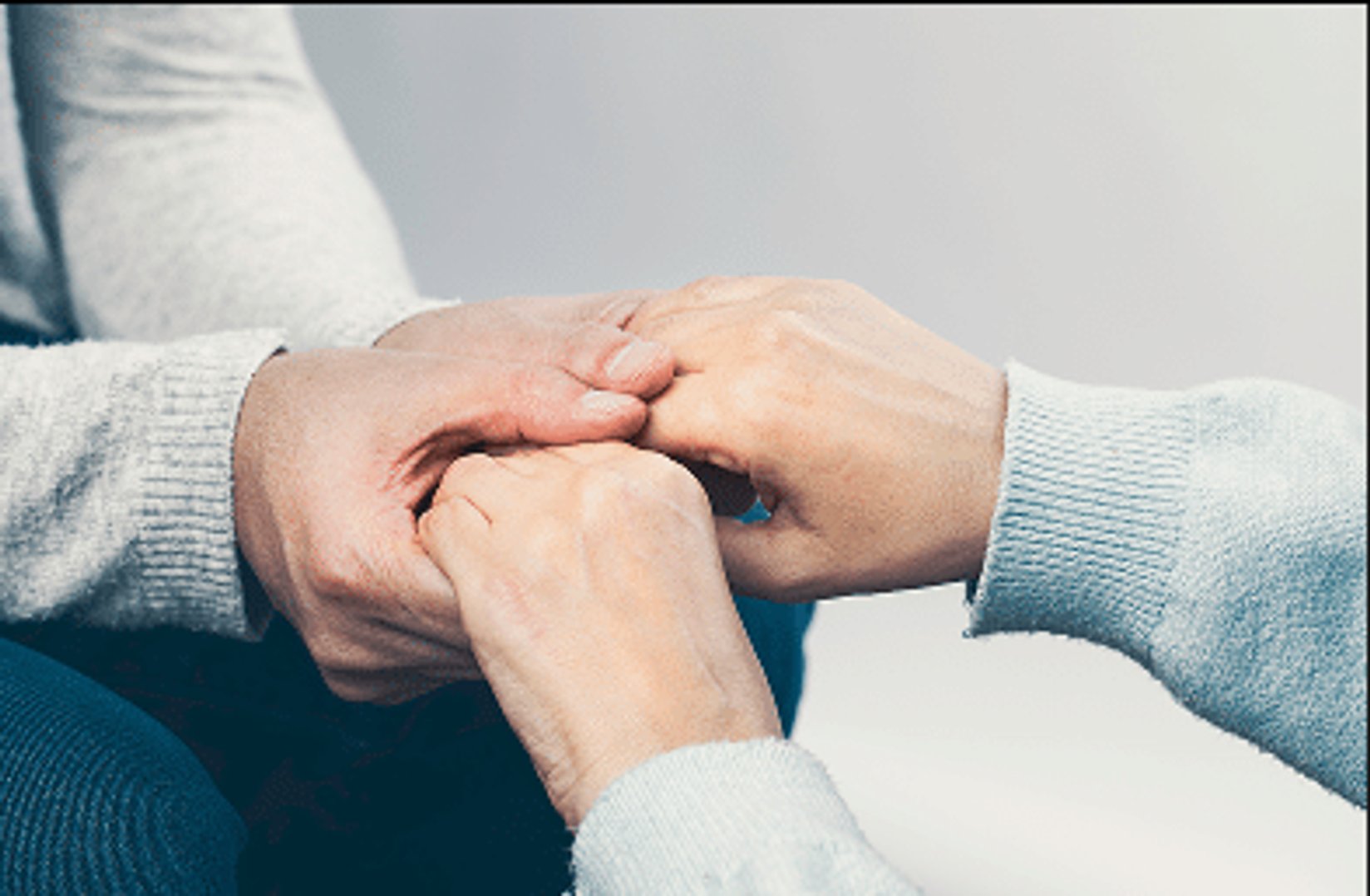 close up of two people holding hands for comfort