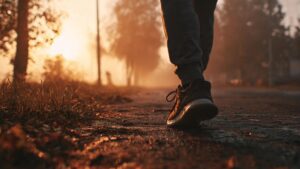 A person walking along a path at sunrise, with one shoe in sharp focus